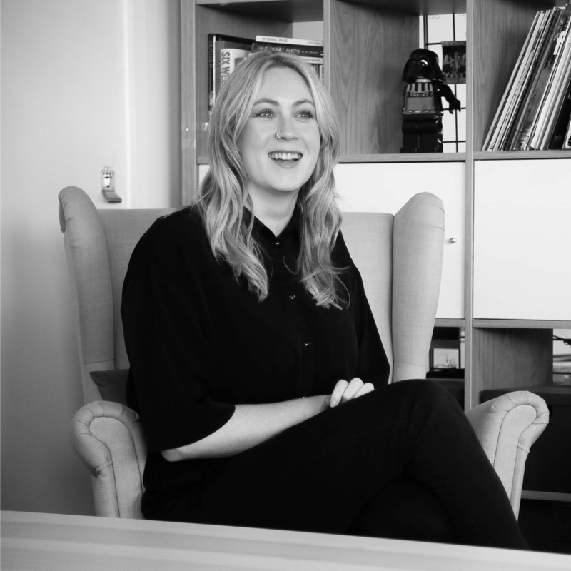 Emma sitting on a chair smiling black and white