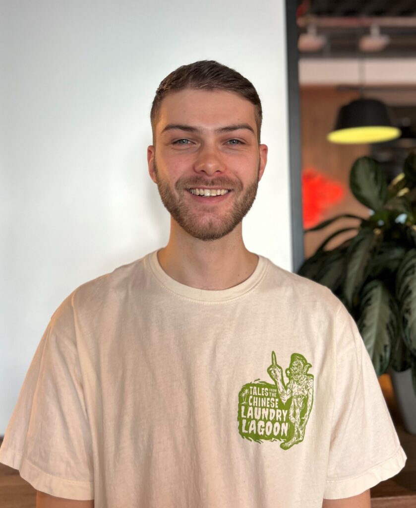 Ollie Evans - smiling with a white wall behind him.