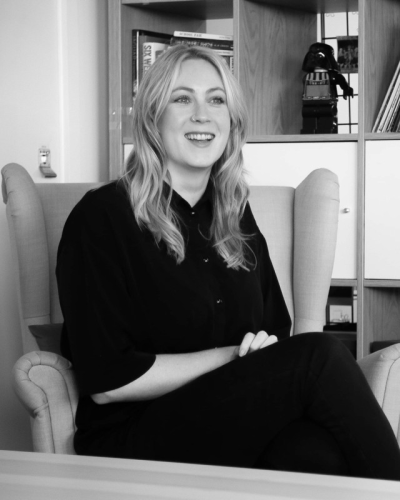 Emma sitting on a chair smiling black and white