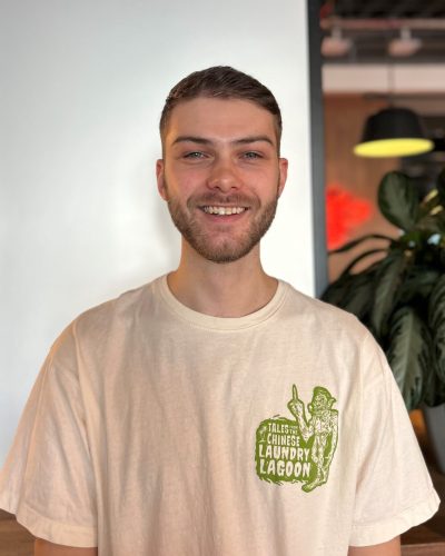 Ollie Evans - smiling with a white wall behind him.